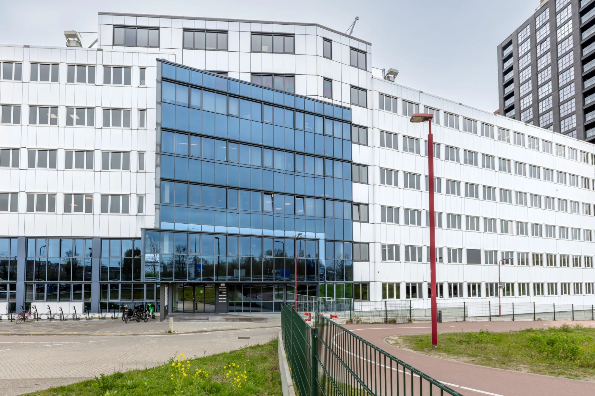 Buitenaanzicht van het kantoorpand in Nieuwegein met witte gevel, glazen entreegedeelte en fietsenstalling