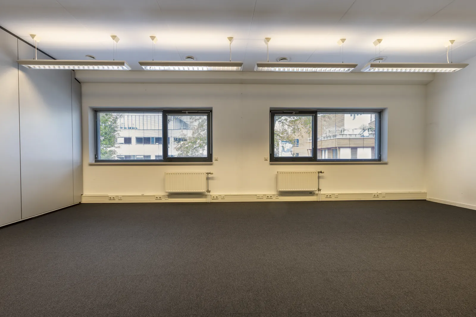 Ruim atrium bij FlexOffiZ Delft met open stalen trap en lichte loungebanken