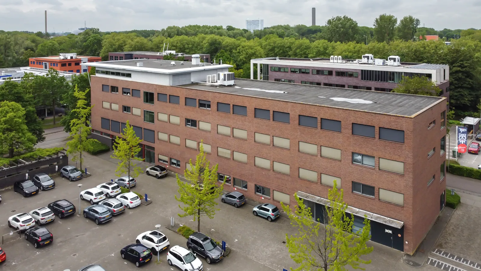 Achterzijde kantoorpand FlexOffiZ Delft met ruim parkeerterrein en laadpalen