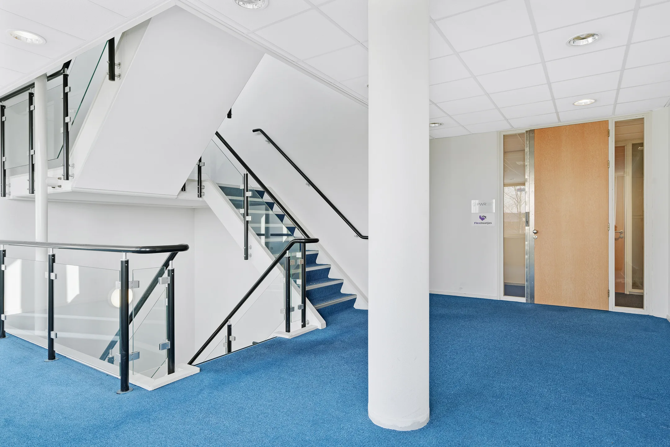 Trappenhuis naar de kantoorverdieping met blauwe vloerbedekking